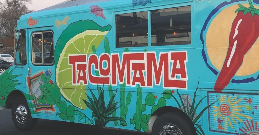 A colorful food truck with a lime and chili pepper on it is parked in a parking lot.
