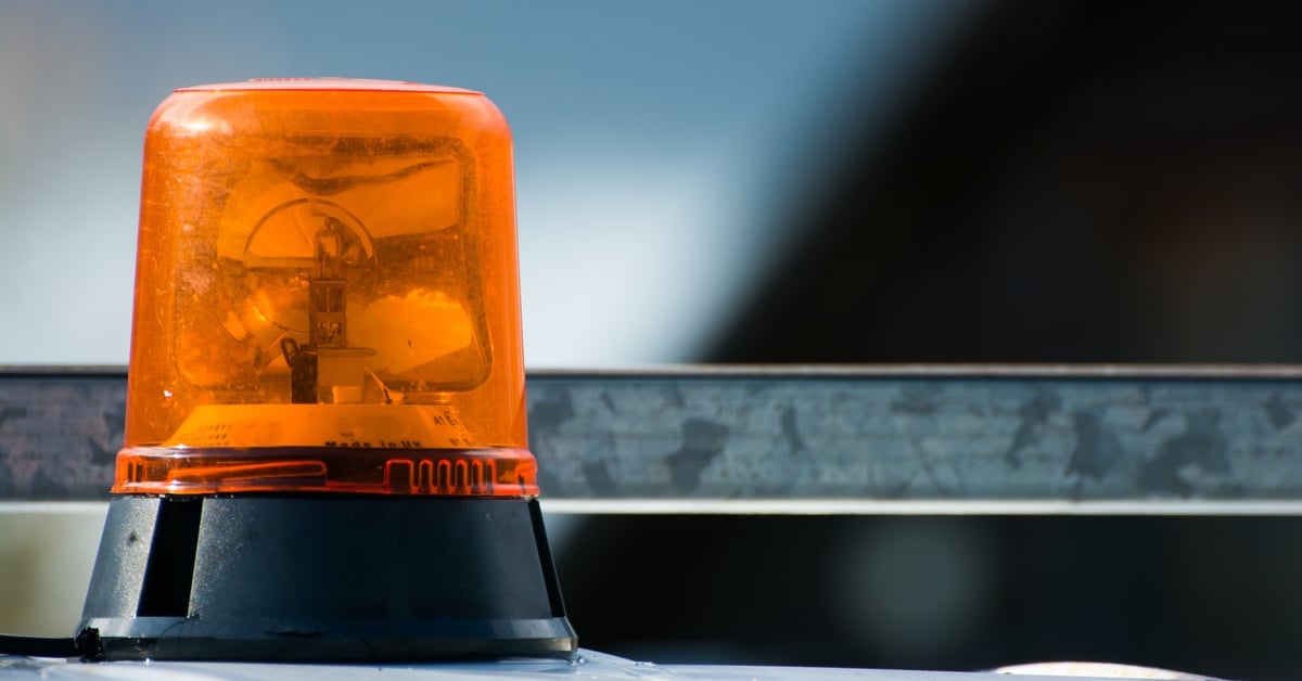 A close-up of an amber beacon light installed on top of a white vehicle. The light is magnetically mounted.