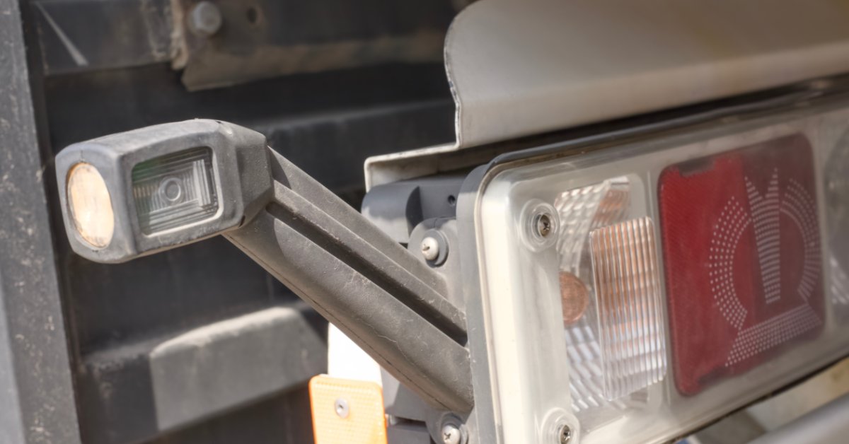 A truck trailer rear light assembly with red and clear lenses beside a small marker light on a gray arm.